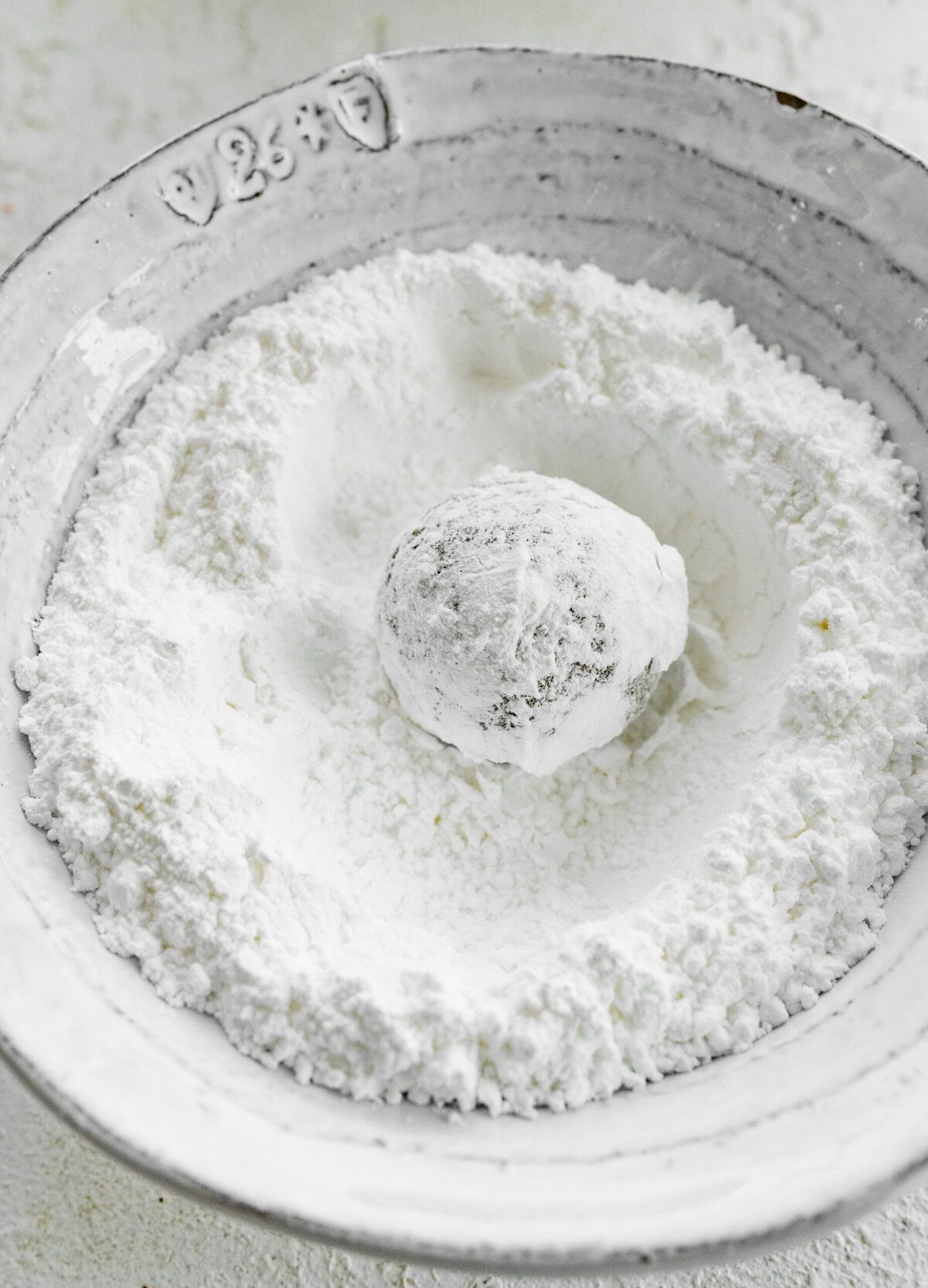 Making Italian Pistachio Cookies- roll the little cookie dough ball in powdered sugar.