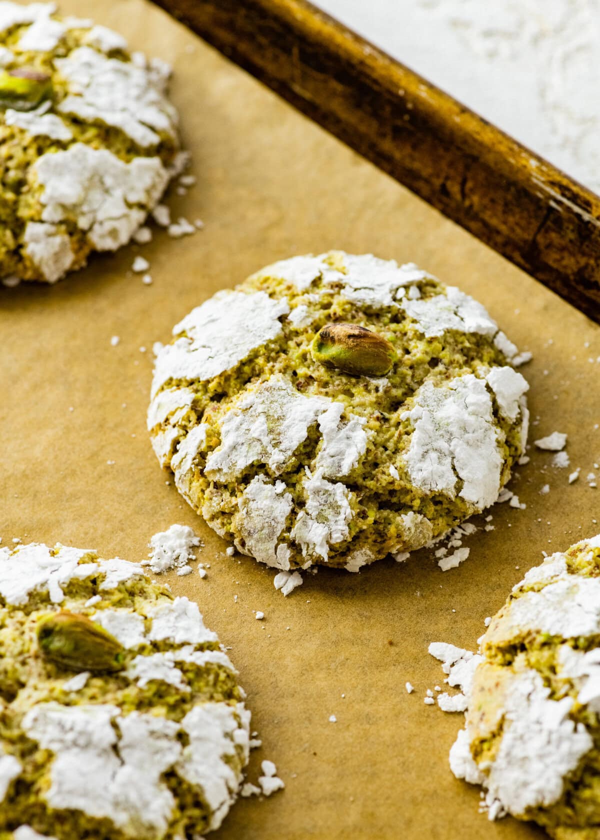 Baked pistachio cookies cooling on a baking sheet.