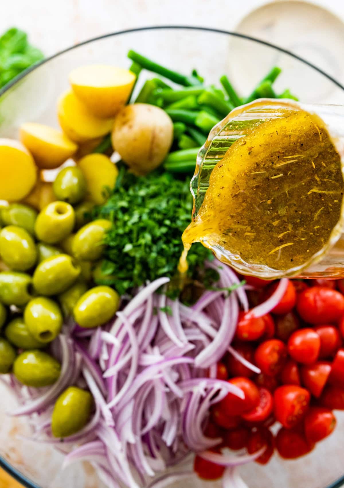 how to make Italian potato salad recipe: pouring Italian vinaigrette dressing over the salad ingredients.