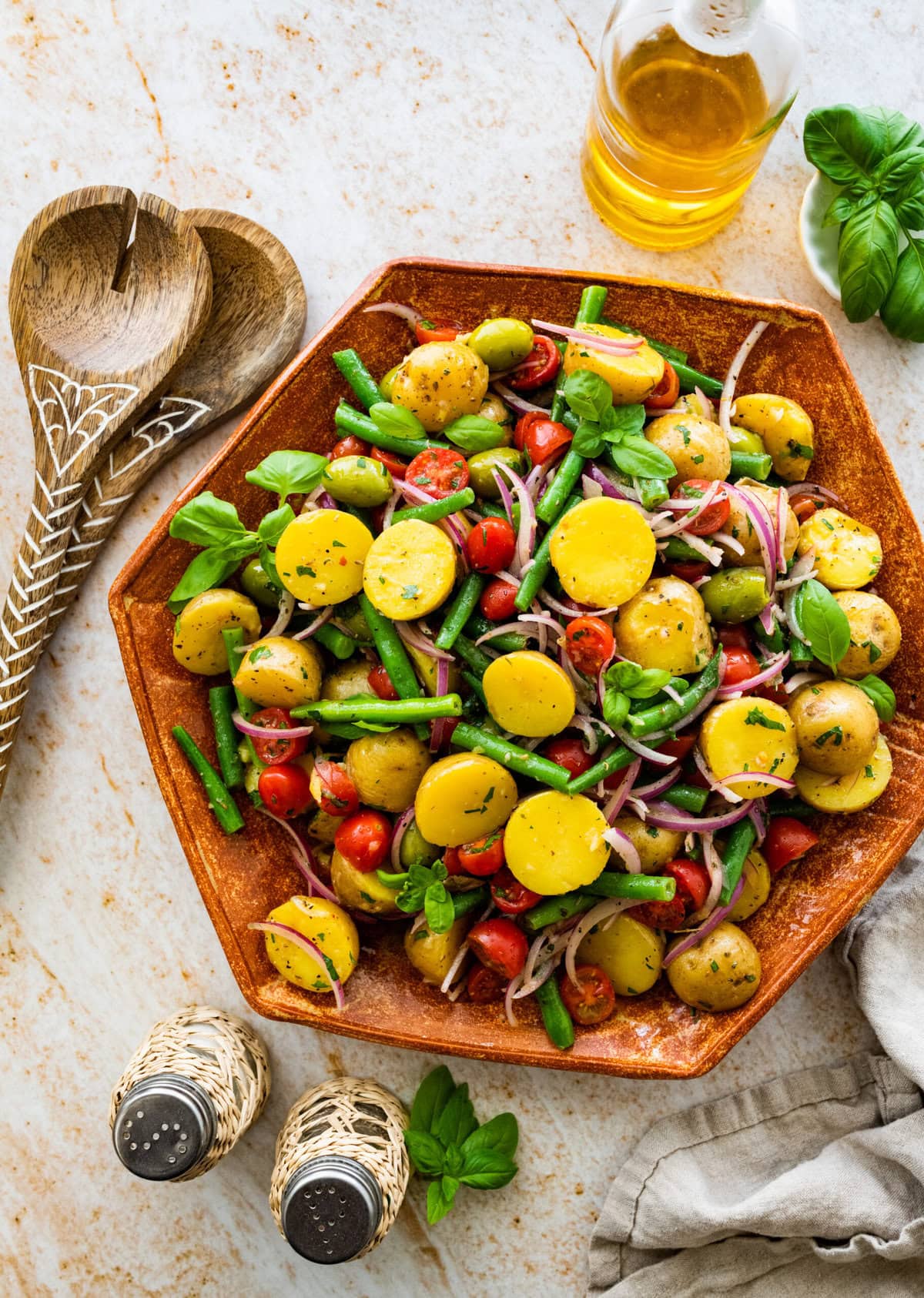 Italian potato salad in a wooden serving platter with wooden servers on the side.