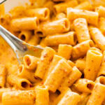 Nduja pasta sauce and pasta in a serving dish Large spoon holding one serving of pasta.