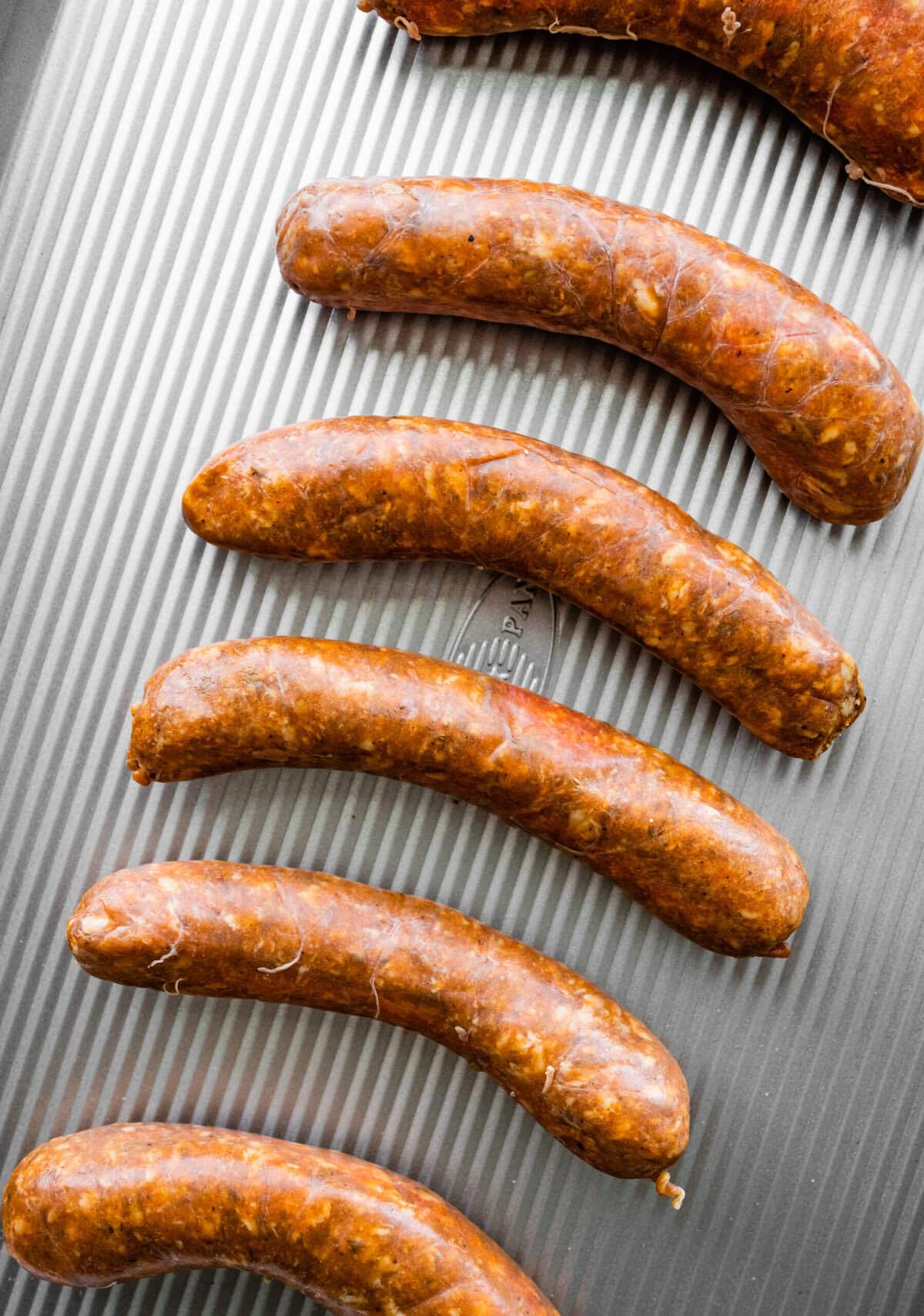 uncooked Italian sausage on a baking sheet.