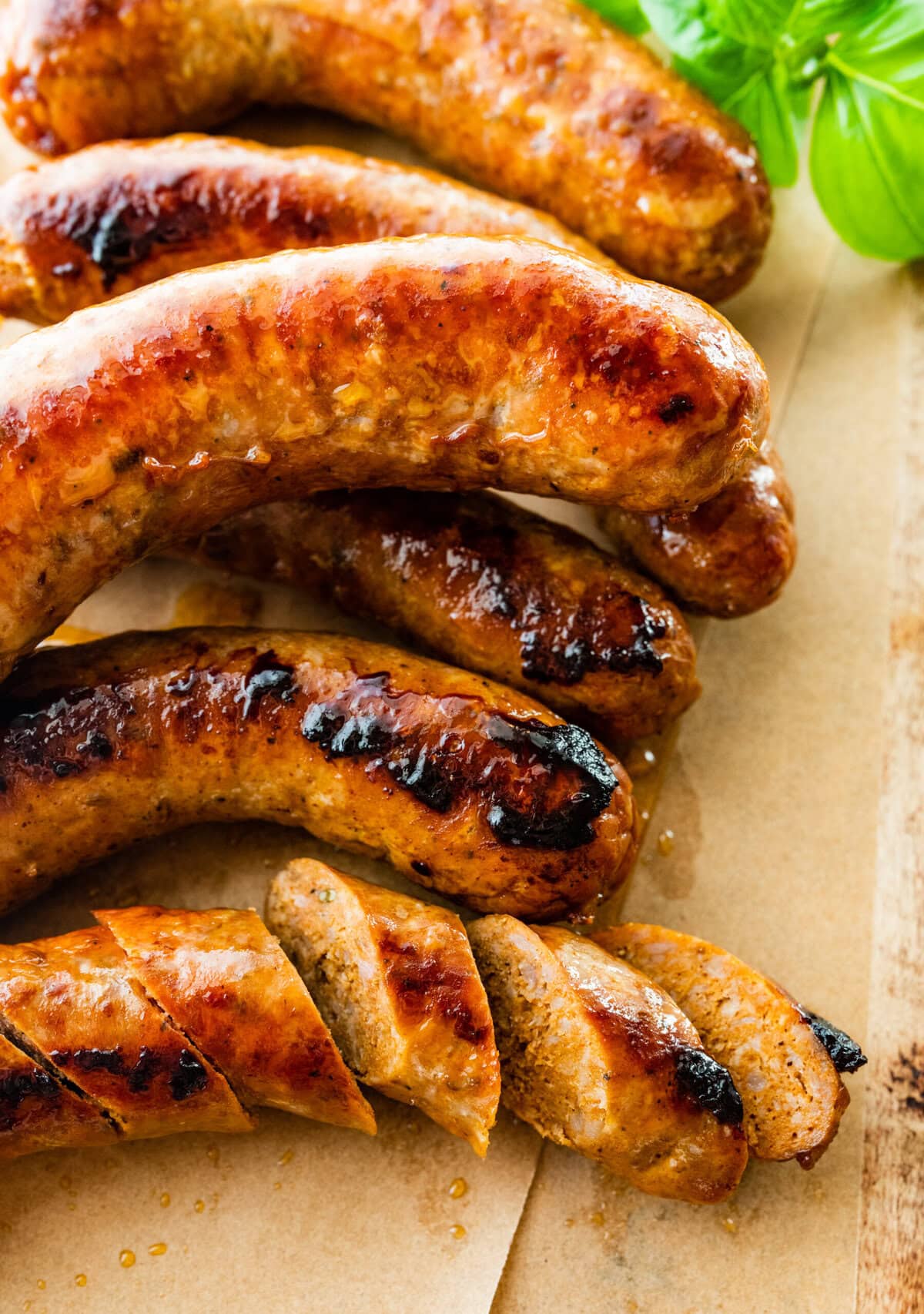 Italian sausages on parchment paper and wood board. One sausage cut into pieces.