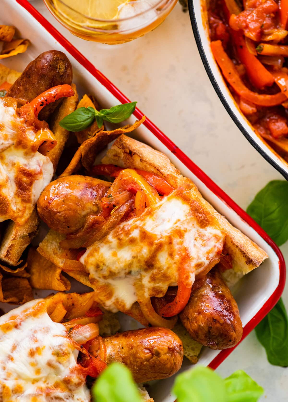 All the Italian sausage sandwiches on a platter with basil on the side.