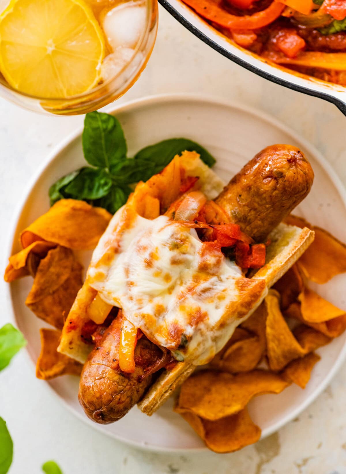 Italian Sausage Sandwich on a plate with chips on the side.