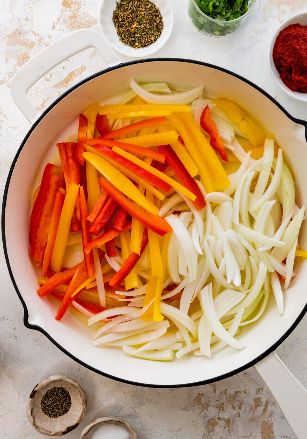 Onions and peppers in pan with oil ready to fry.