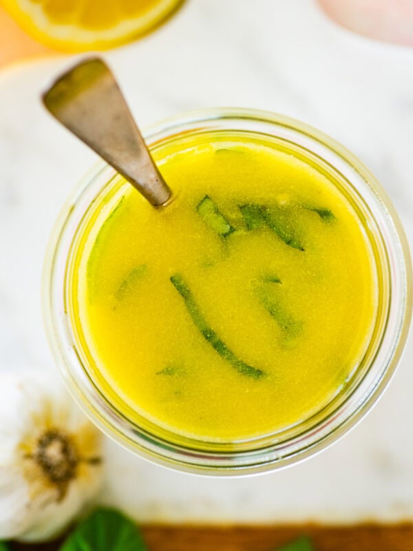 lemon basil vinaigrette on a marble background. Spoon in the jar.