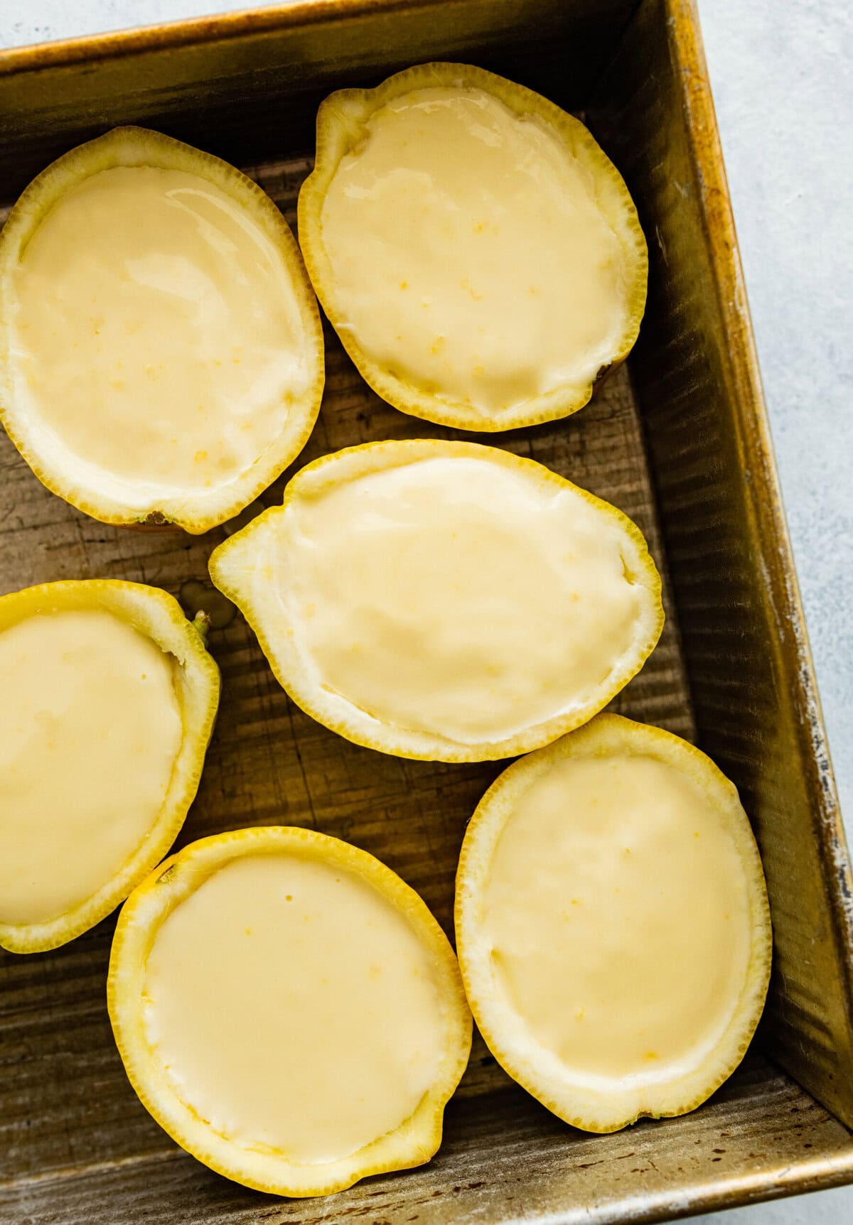 lemon halves in a baking tray with the lemon posset inside. Ready to cool.