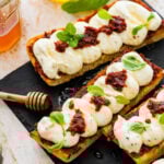 nduja ricotta toast on a black platter with honey drizzle and basil on top as garnish.