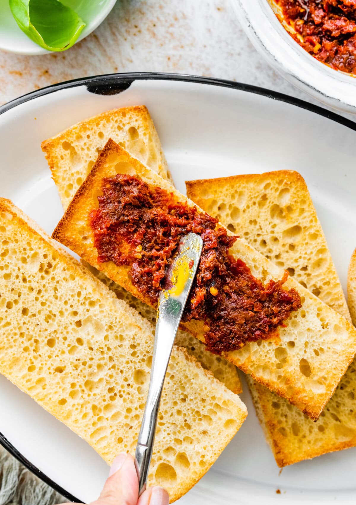 knife spreading nduja on the ciabatta bread.