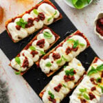 nduja ricotta toast on a black platter with basil on top as garnish.