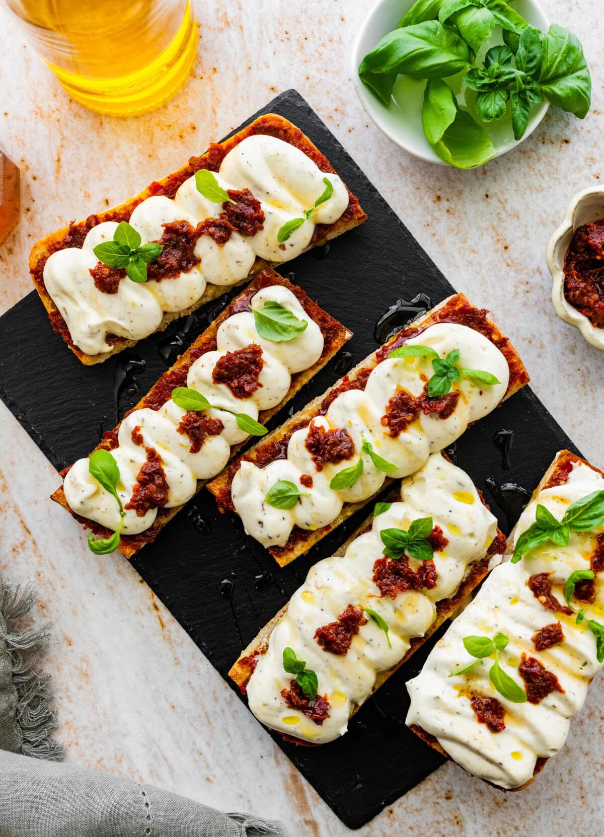 nduja ricotta toast on a black platter with basil on top as garnish.