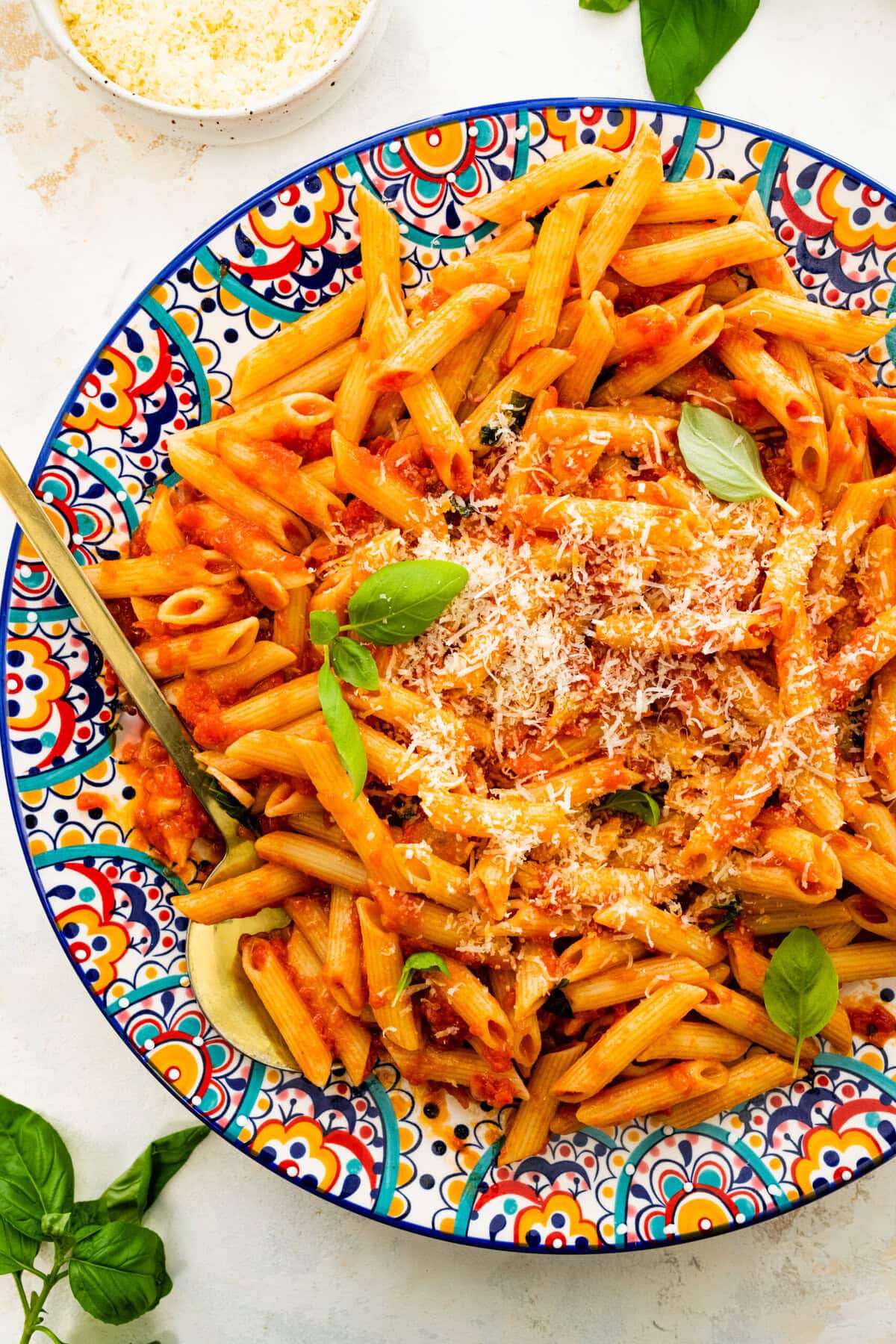 penne pomodoro on a blue and white platter. basil leaves on top.