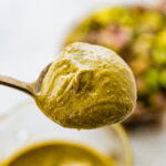 spoon holding portion on the creamy pistachio butter.