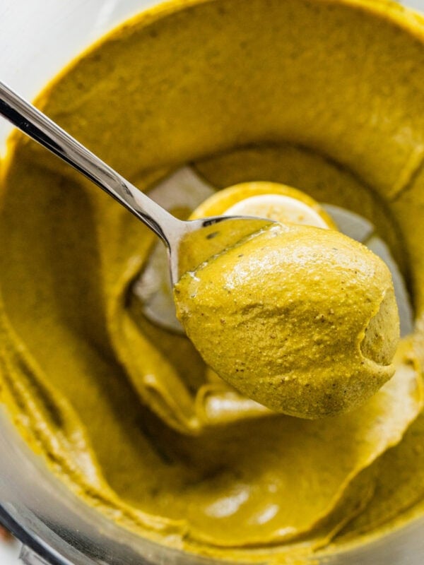 spoon holding pistachio butter over the food processor.