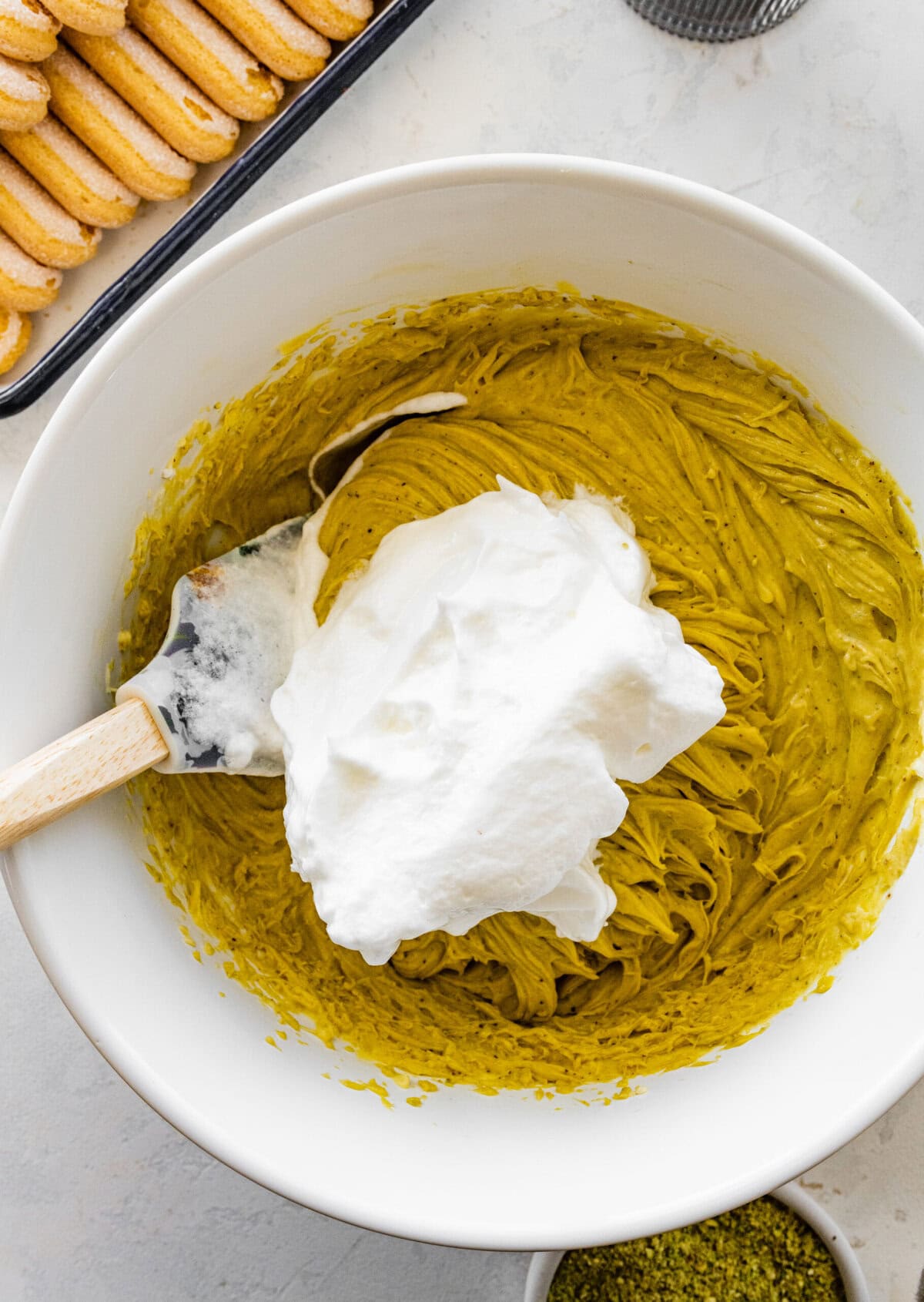 adding egg whites in a bowl with the pistachio mascarpone mixture.
