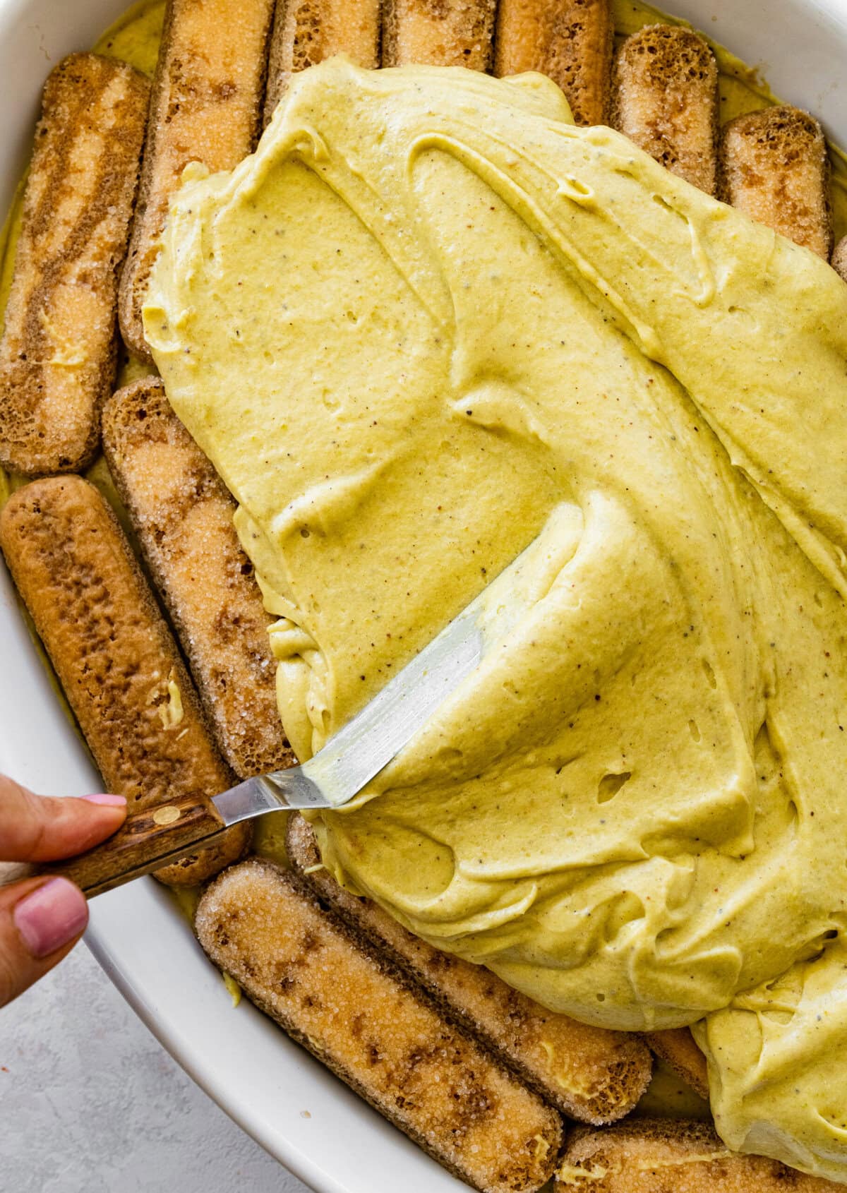 layer the pistachio mascarpone filling over the dipped ladyfingers.