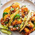 three assembled shrimp tacos on a plate.