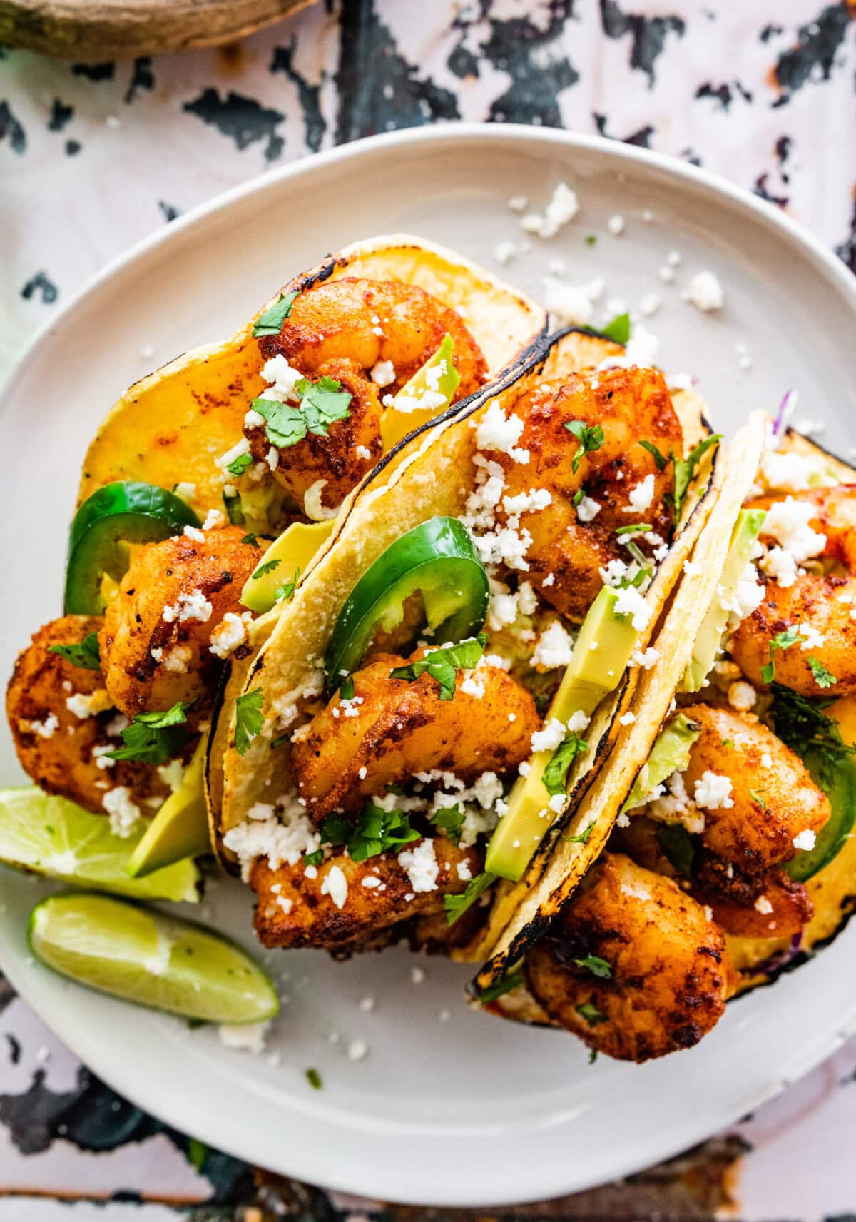 three assembled shrimp tacos on a plate.