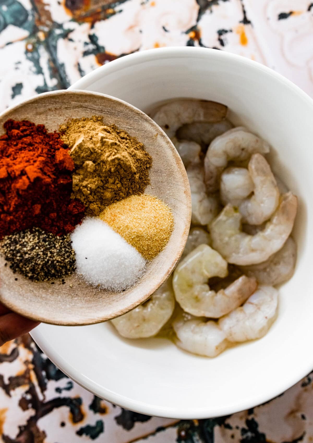 add the seasonings to the bowl of uncooked shrimp.