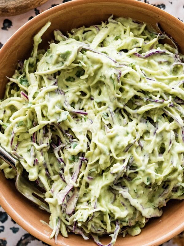 creamy avocado slaw in a bowl with a spoon in it.