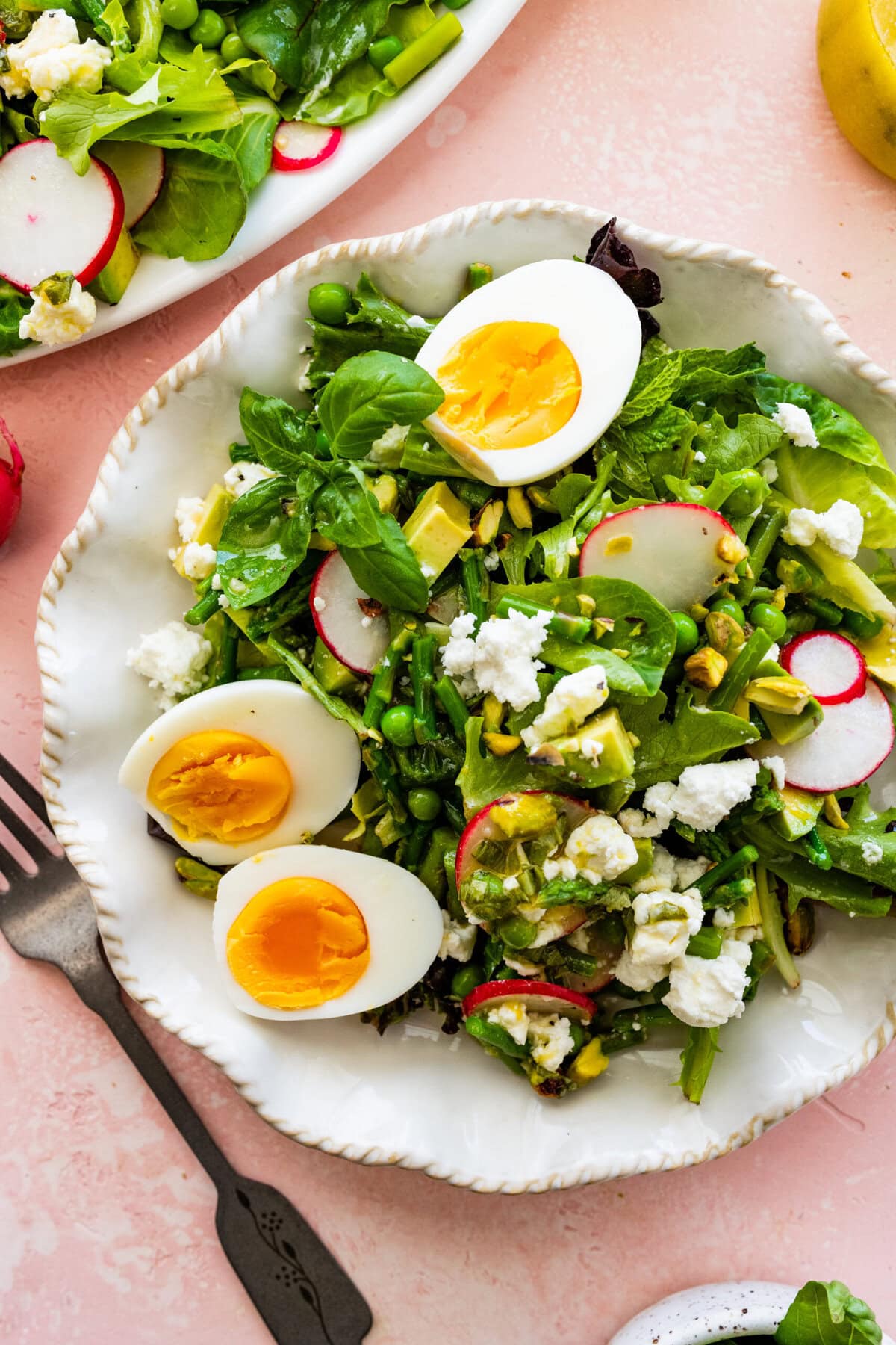 spring salad on a white plate with a fork ready to eat.