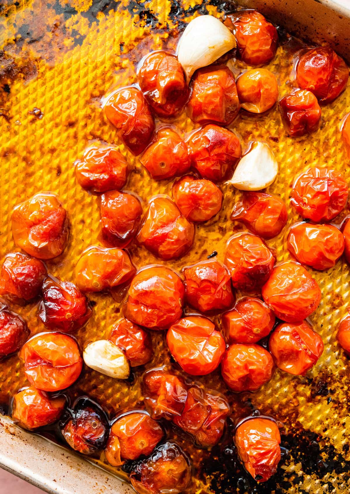 cooked and blistered cherry tomatoes on a cookie sheet.