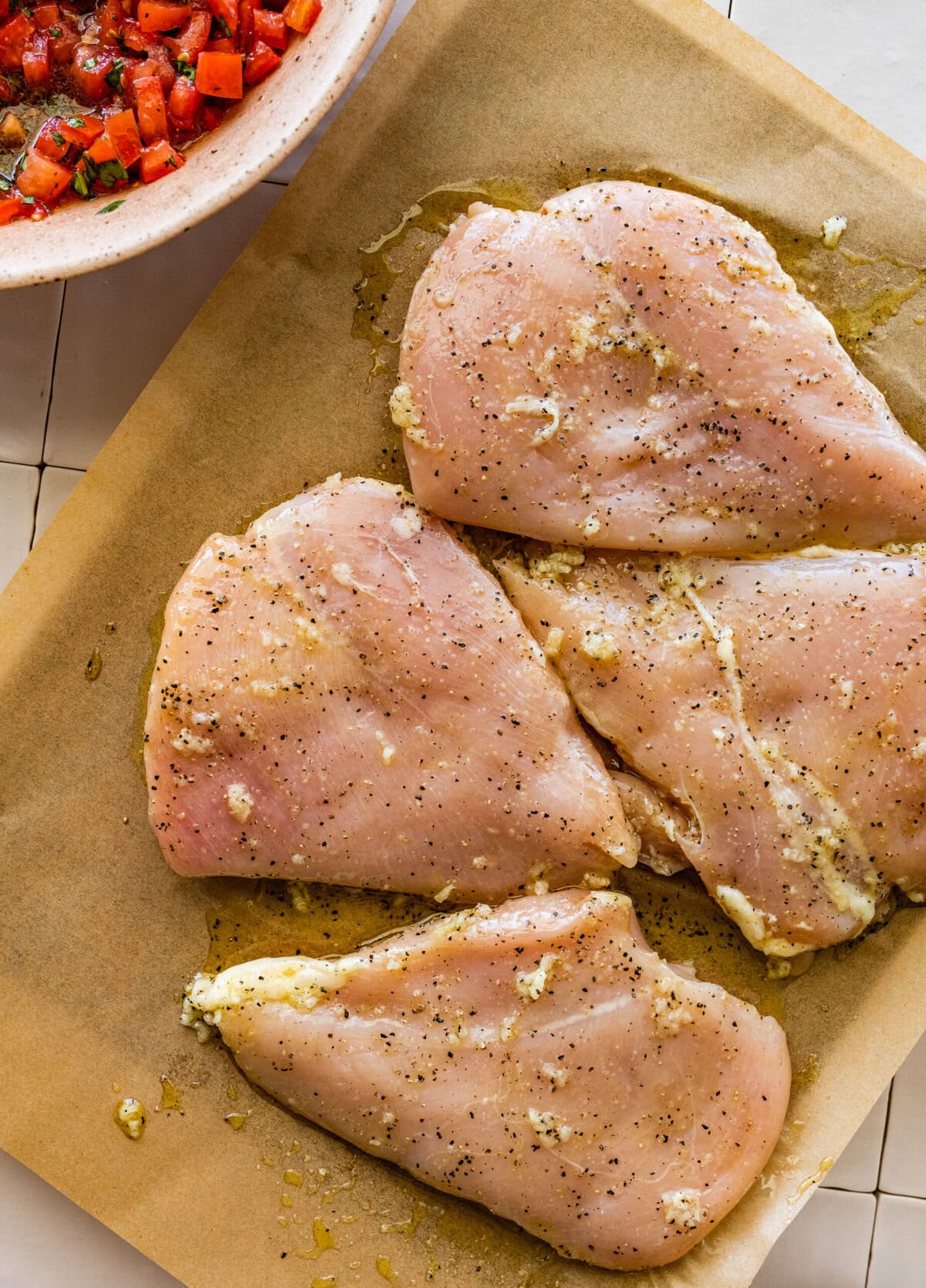 Three chicken breasts on a baking sheet with a bowl of salsa