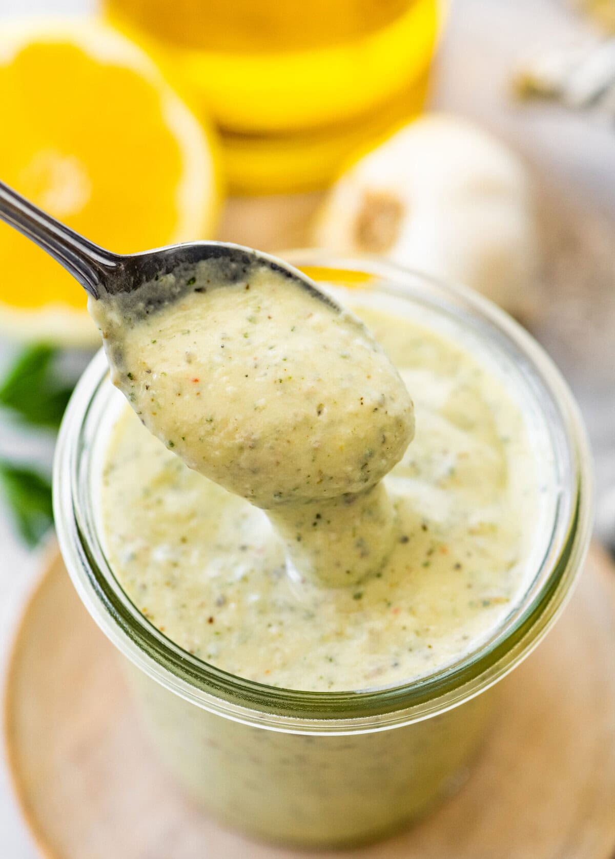 Garlic herb dressing in a jar with a spoon in it.