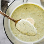 A spoon is lifting a bowl of creamy Italian dressing.