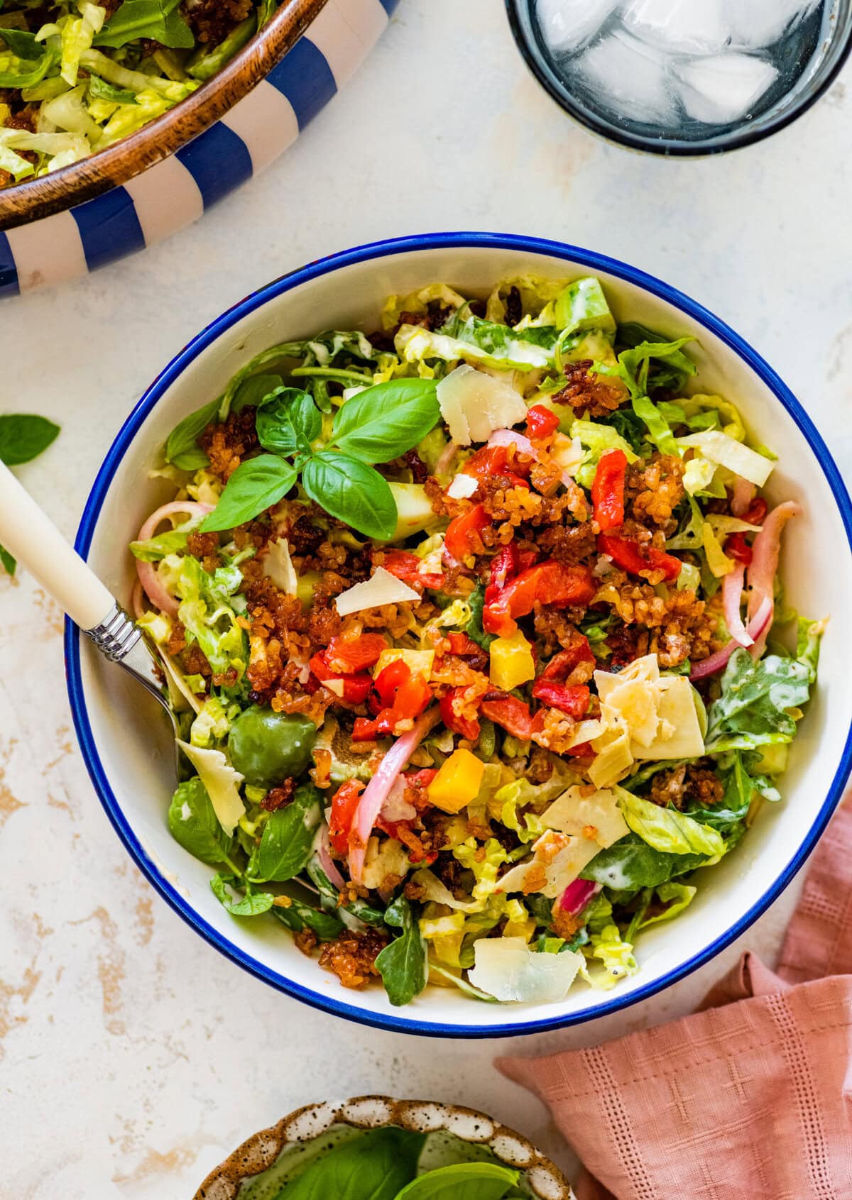A bowl of salad with crispy rice, peppers, onions and other veggies.