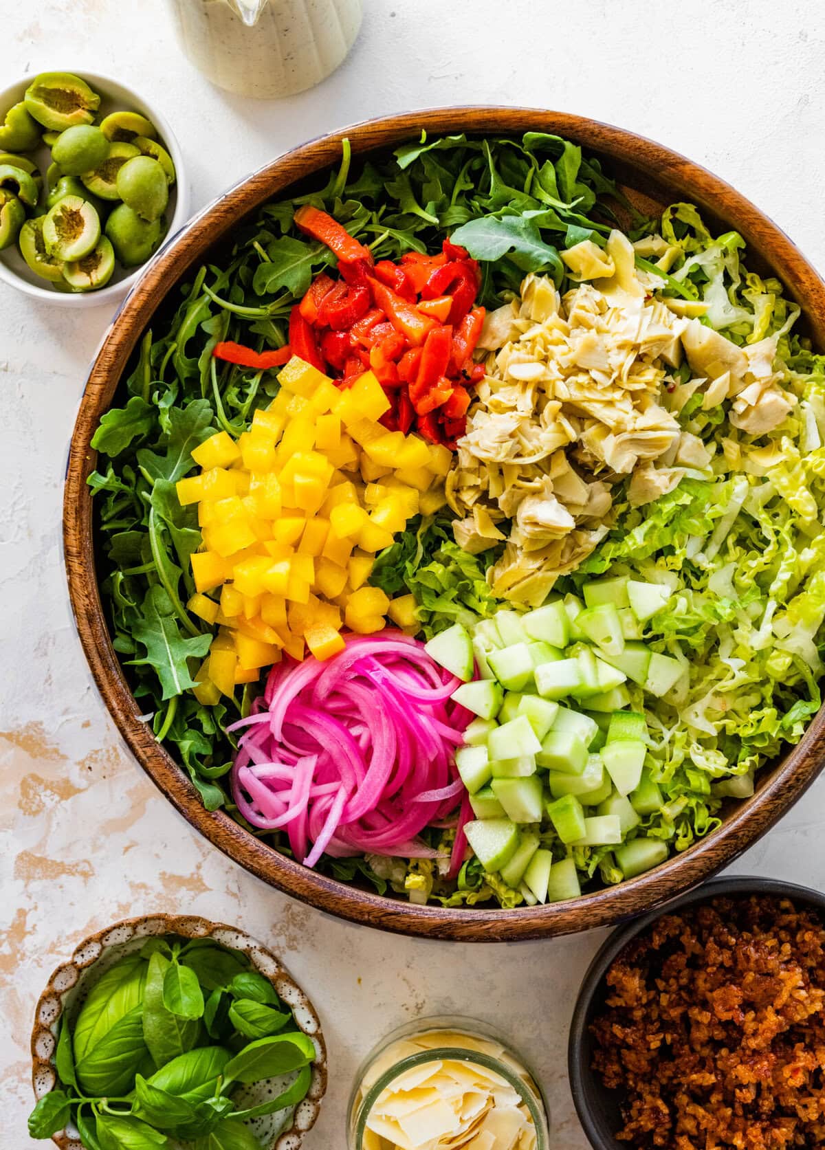 A bowl filled with salad ingredients and a wooden cutting board