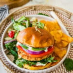 A chicken burger with a side salad and chips.