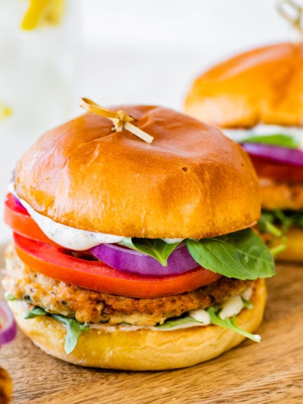 Three chicken burgers with lettuce, tomatoes and onions