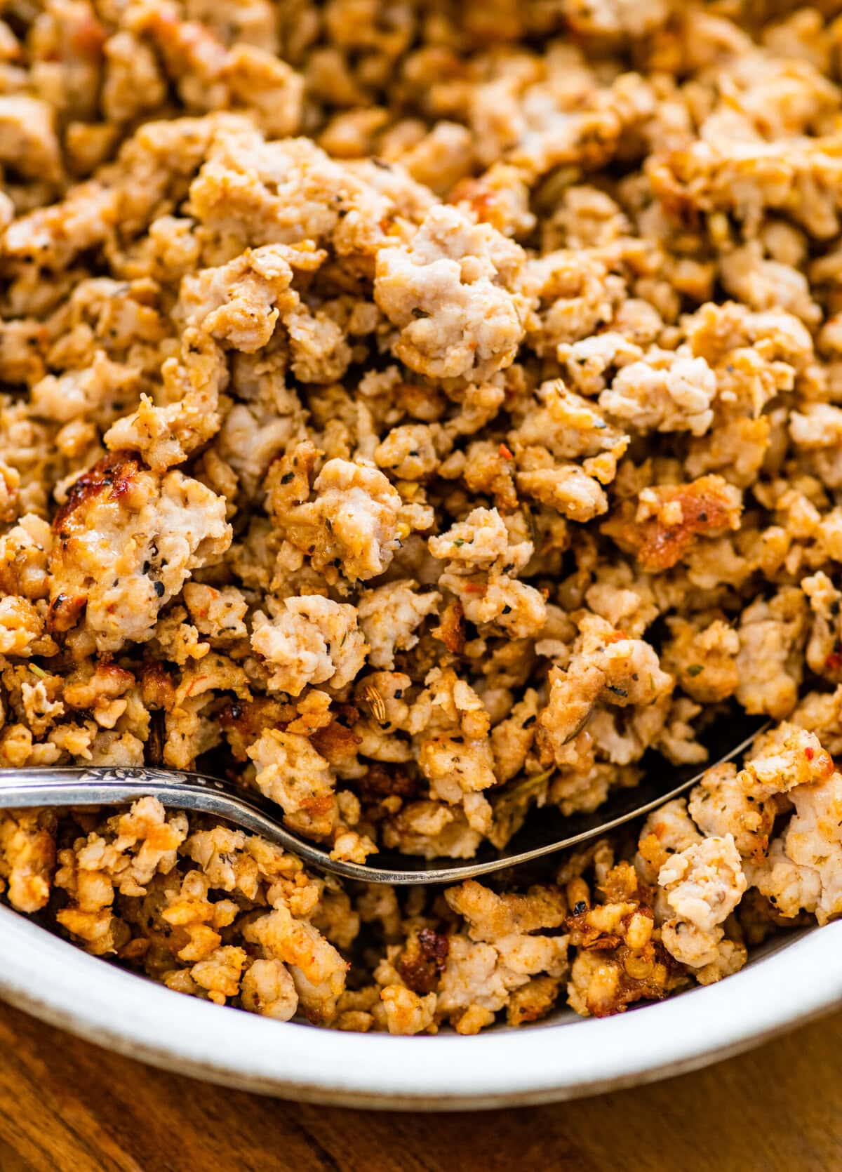 homemade Italian sausage cooked and crispy in a bowl with a spoon.