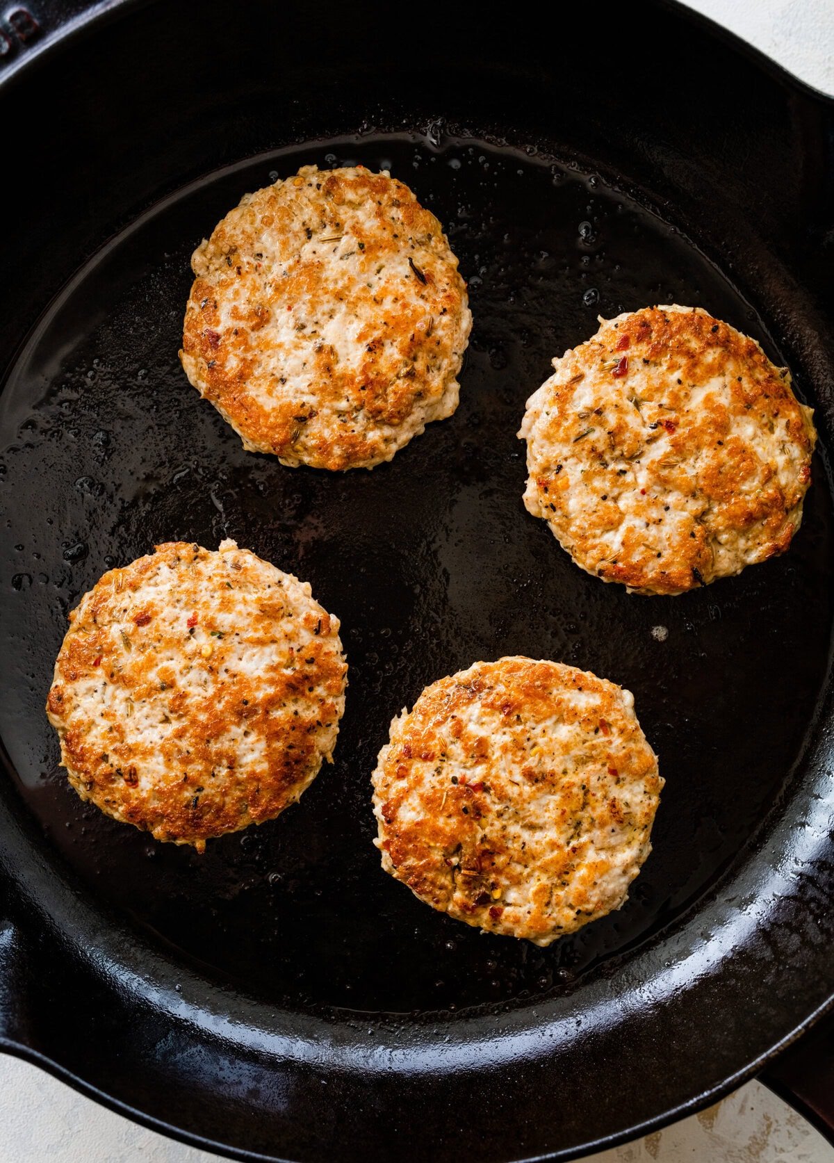 cooked round Italian sausage patties in cast iron pan.