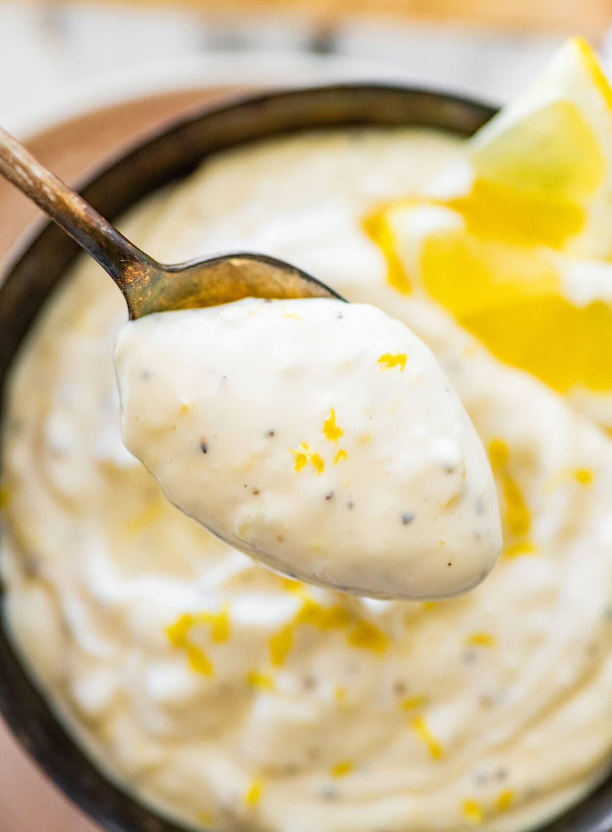 Lemon garlic aioli dip in a bowl with lemon slices.