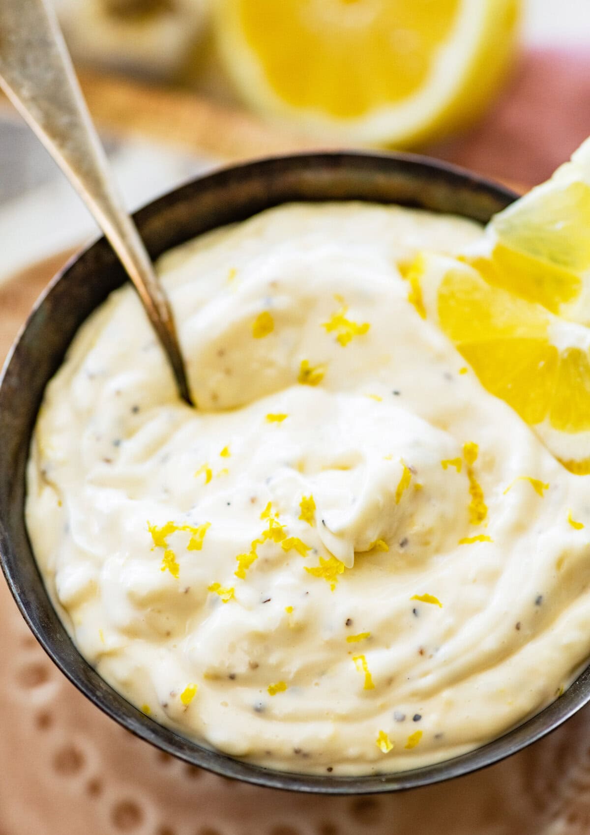 Lemon garlic aioli dip in a bowl with lemon slices. Spoon in bowl.