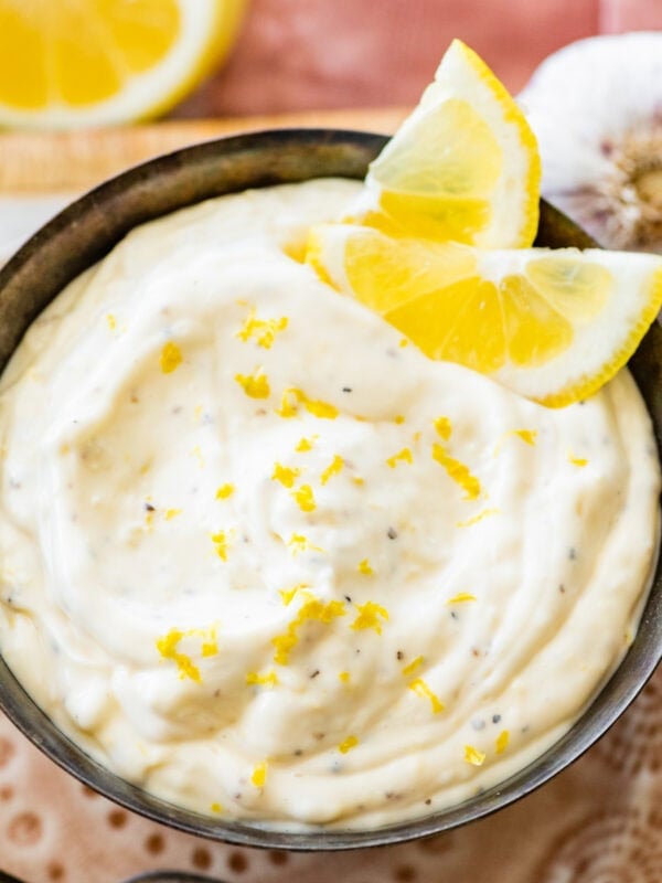 Lemon garlic aioli dip in a bowl with lemon slices.