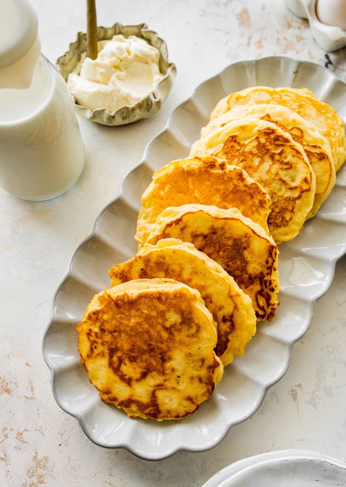 A plate of pancakes with butter and milk