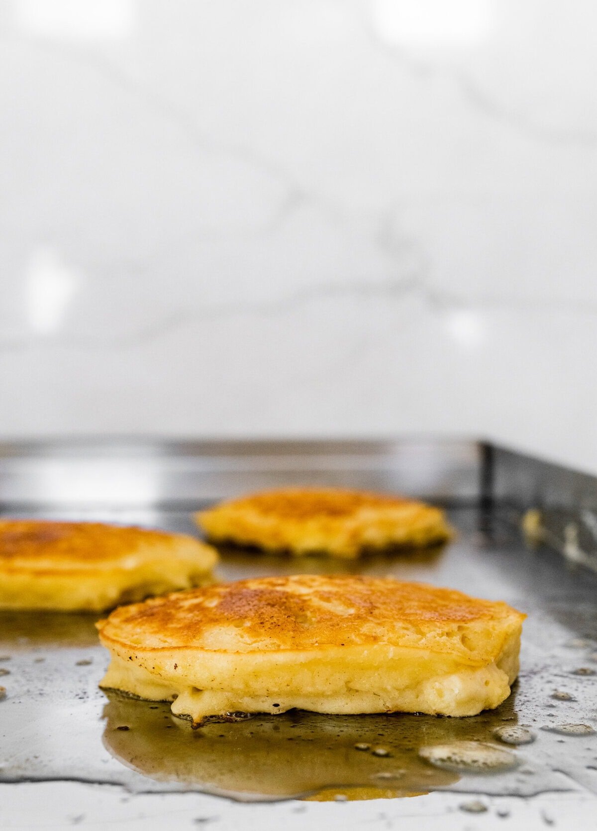 Four pancakes are being cooked on a pan