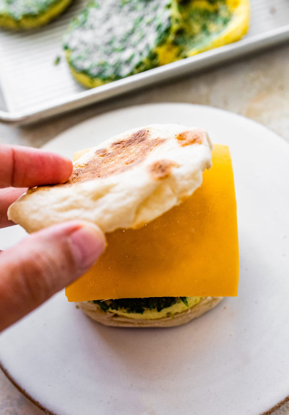 A person holding a sandwich with cheese and spinach.