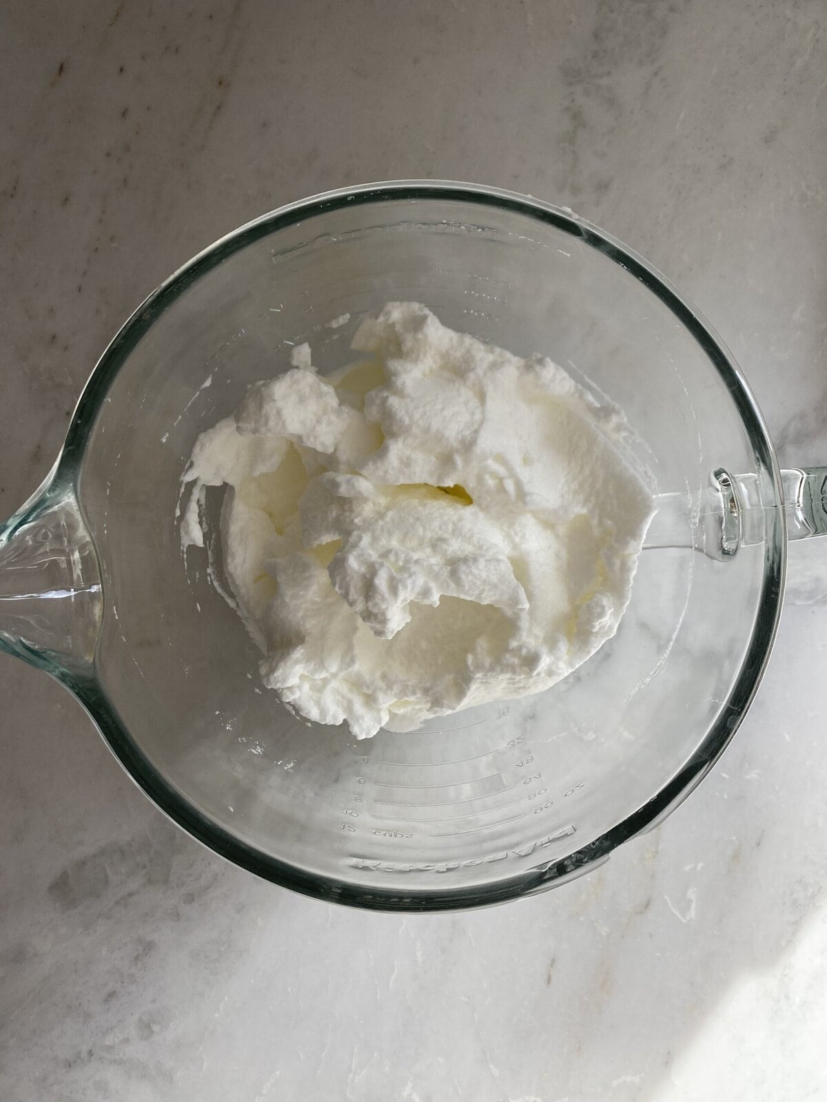 Egg whites beat in a glass bowl.