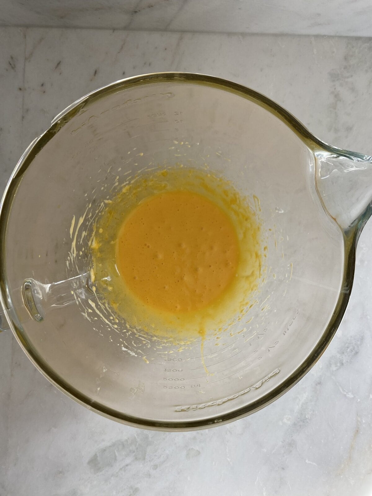 Egg yolks and sugar mixed together in a glass bowl.