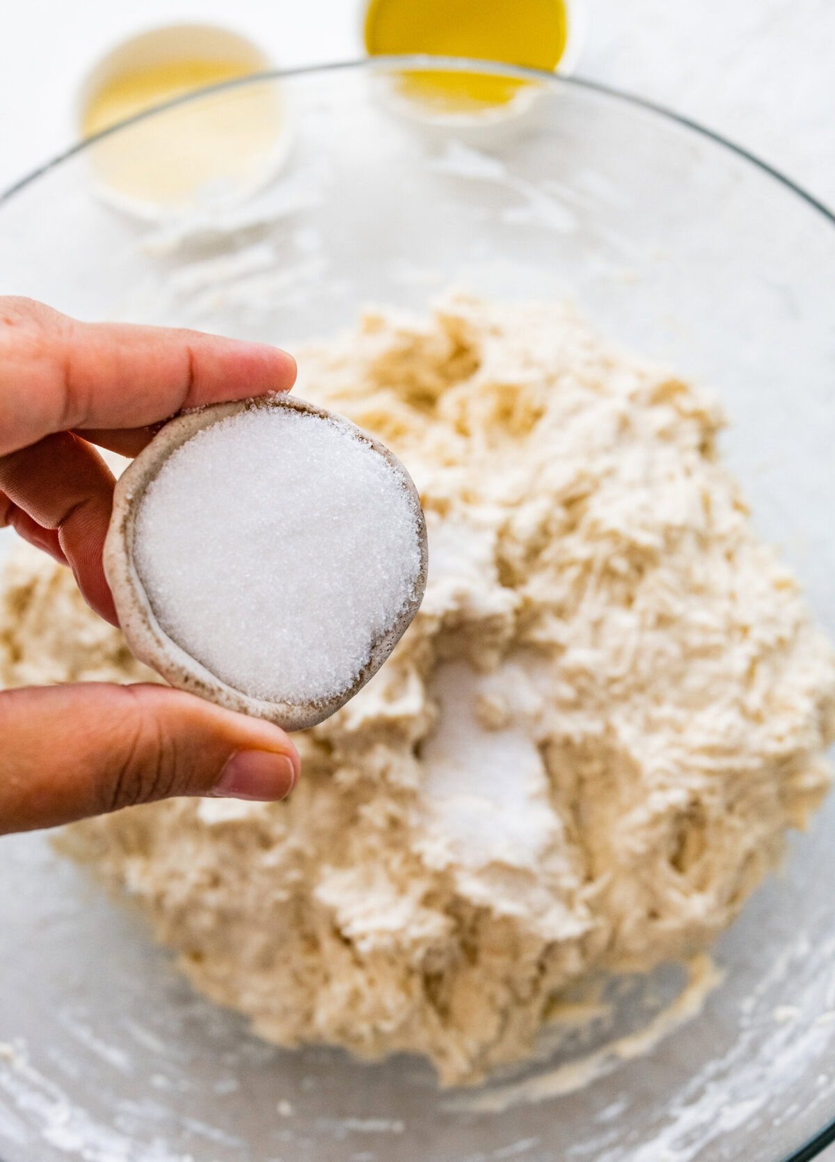 A person holding a piece of salt to add to the dough.