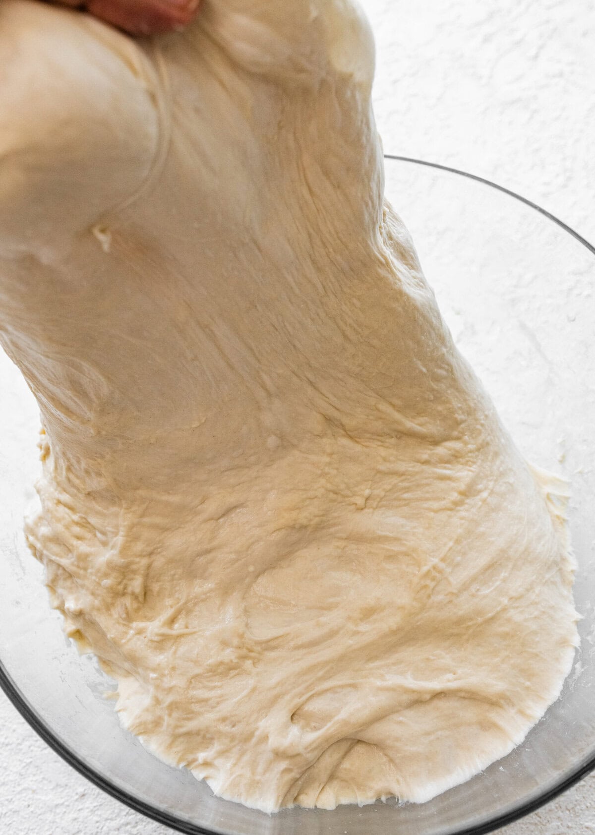 A person is holding a the stretched dough.