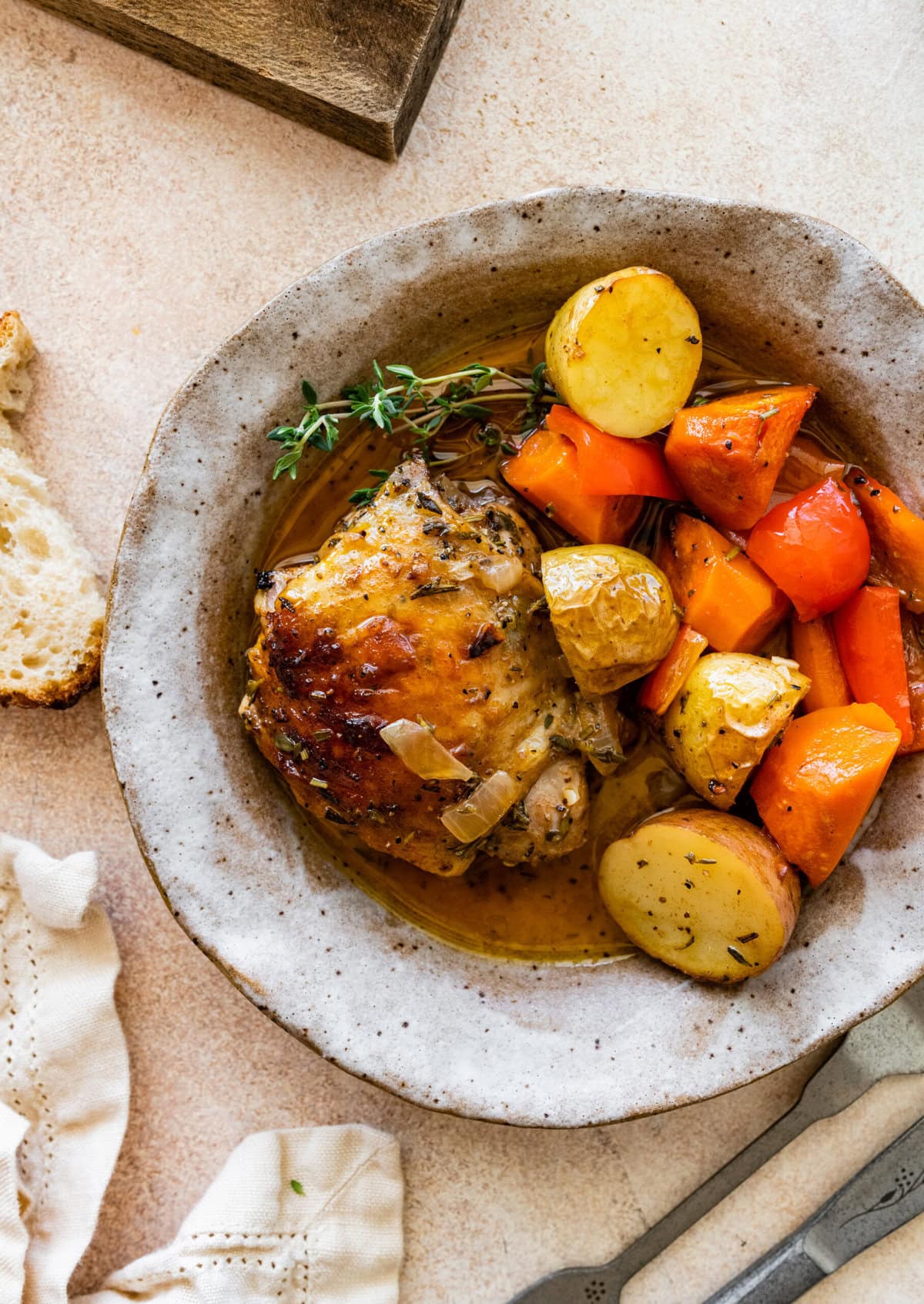Chicken with potatoes and carrots in a white bowl.
