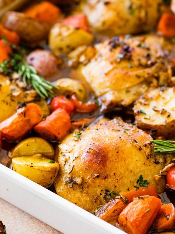 A pan of baked chicken, potatoes, carrots and other vegetables.