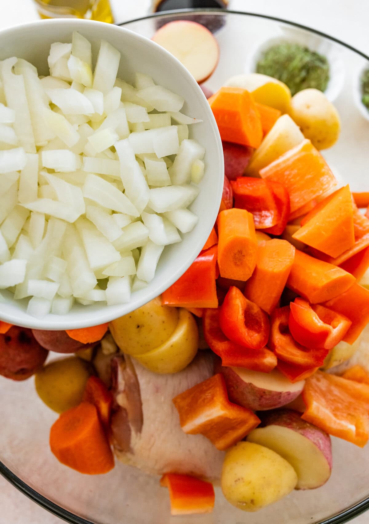 A bowl of chopped vegetables and a plate of chicken.