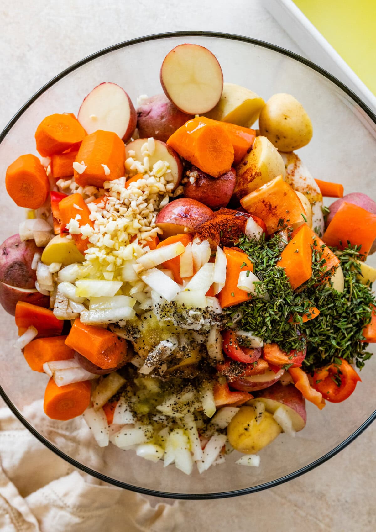 Chicken thighs, potatoes, carrots, onions, and herbs on a white background.